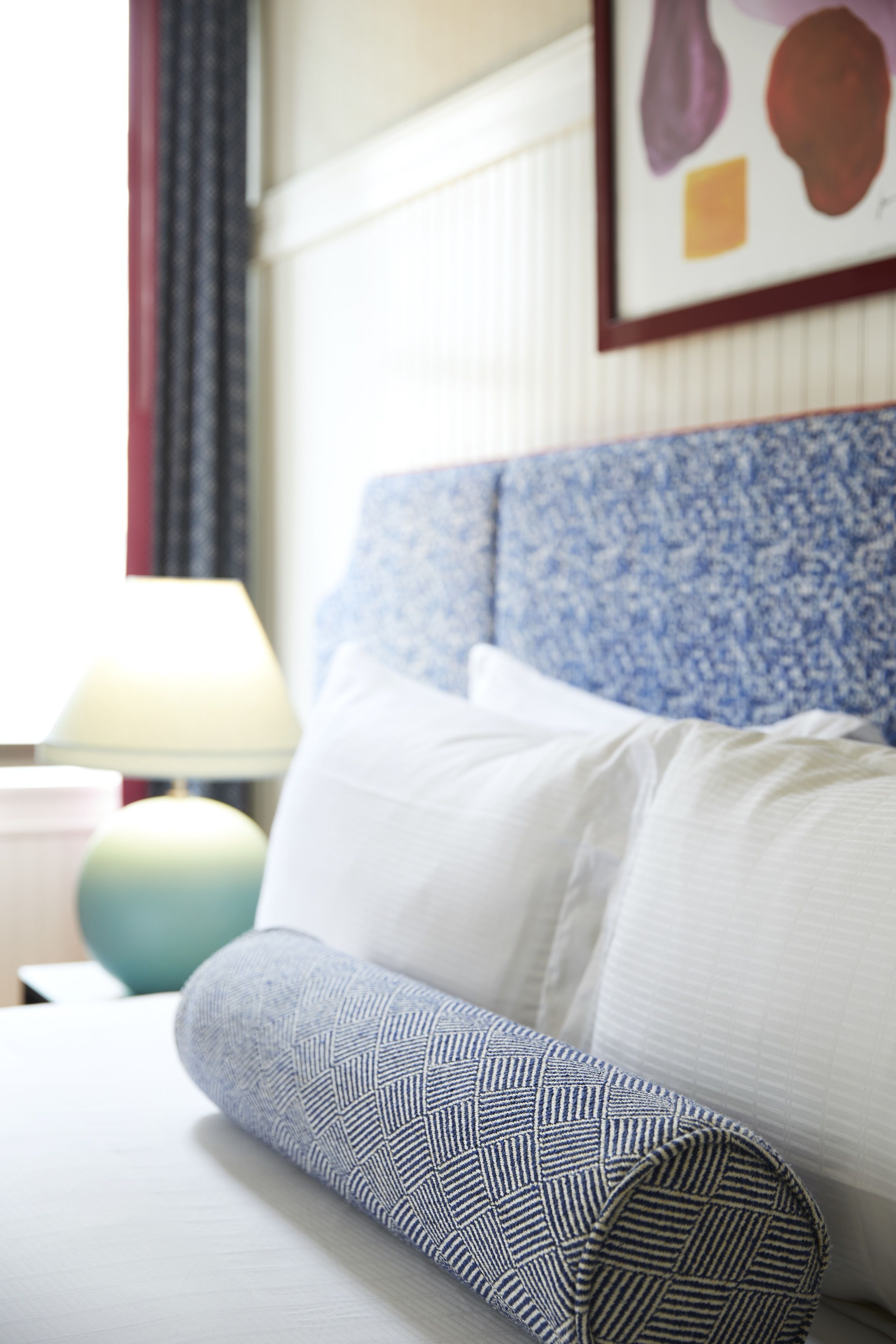 A neatly made bed with a patterned pillow and a headboard with a floral design.