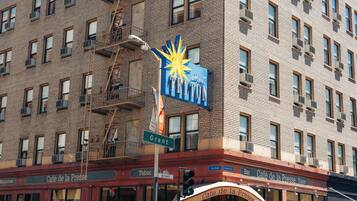 A hotel with a prominent sign reading "PRITON" and a starburst design. The building has multiple windows and a fire escape.
