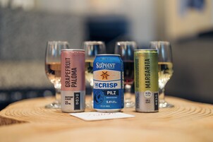 Three cans of beer and three glasses on a wooden surface.
