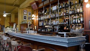 A bar area with a long counter, multiple shelves of liquor bottles, and several chairs. - Hotel Triton Union Square San Francisco (San Francisco)
