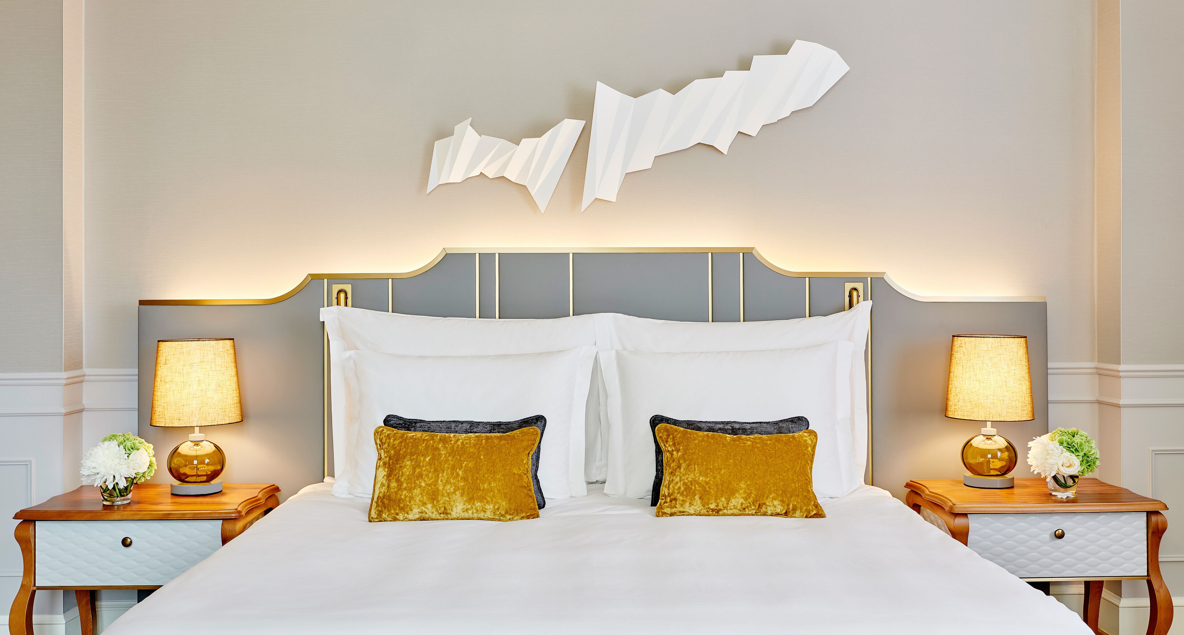 Ein Hotelzimmer mit einem großen Bett, zwei Nachttischen mit Lampen und einem dekorativen Wandbild darüber.