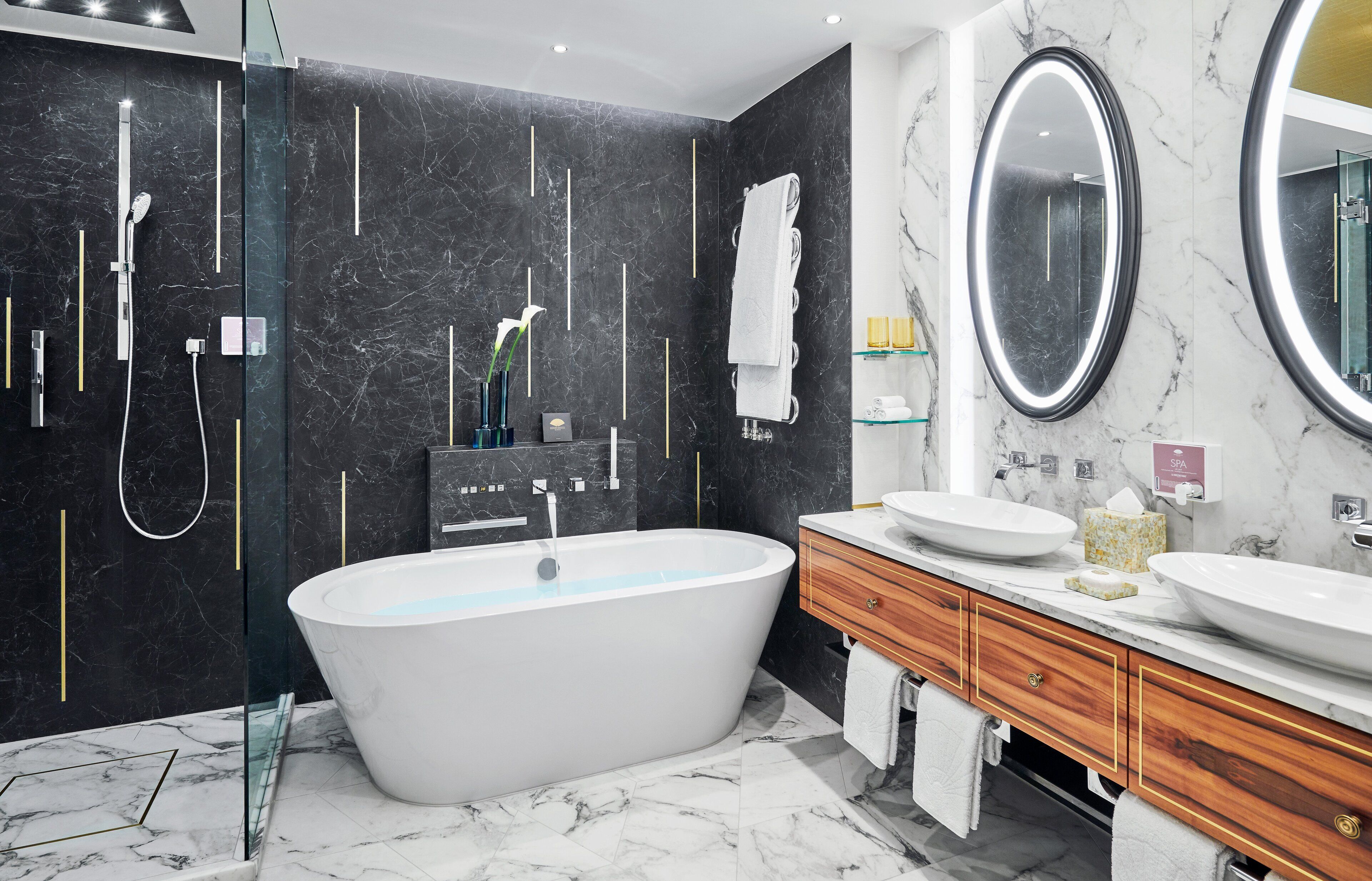 Ein modernes Badezimmer mit einer freistehenden Badewanne, einem großen Spiegel und einem Waschtisch mit zwei Becken.