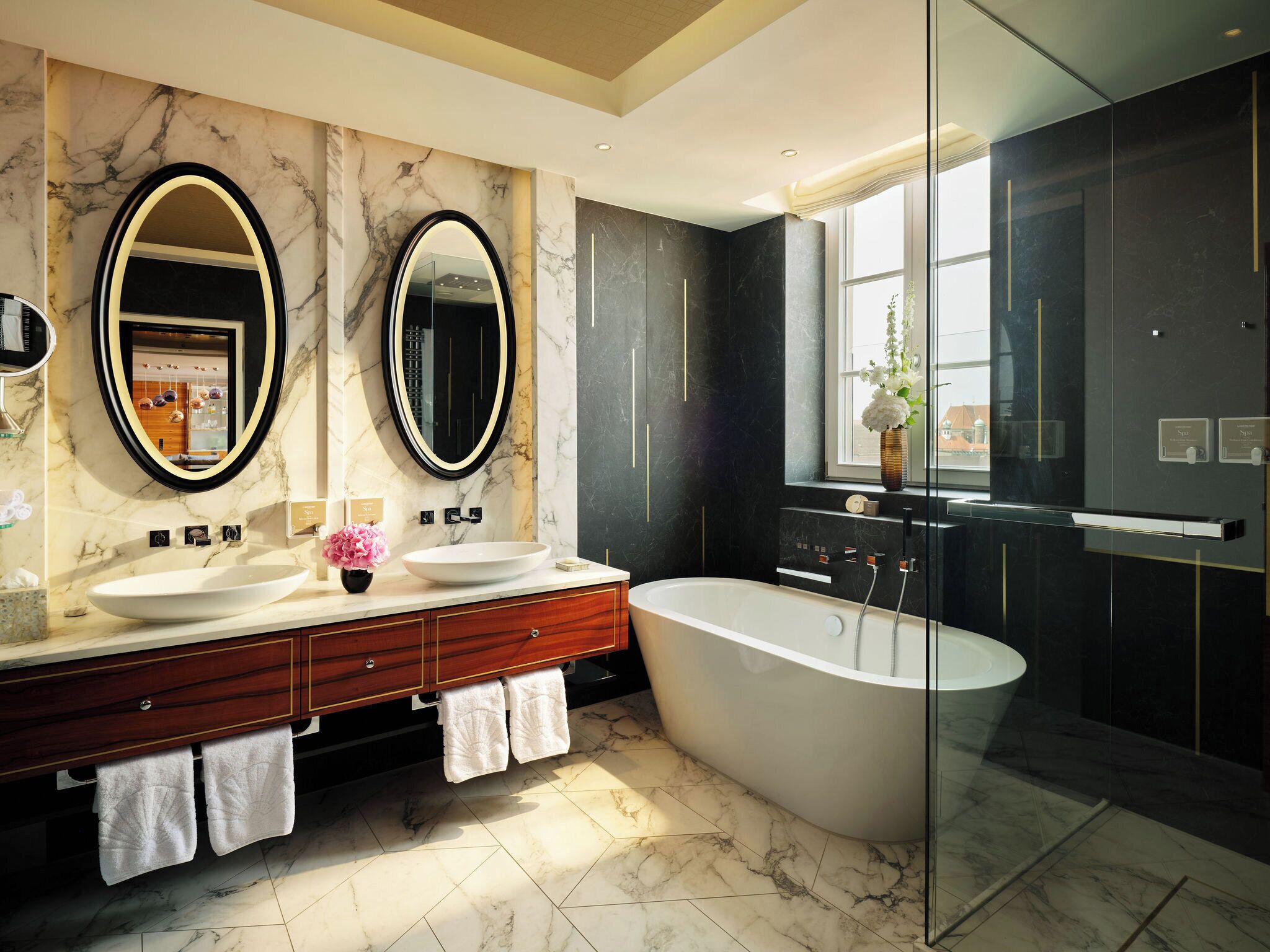 Un baño moderno con dos lavamanos, una bañera independiente grande y una zona de ducha con paredes de vidrio.