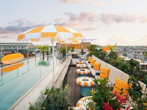A rooftop pool area with lounge chairs, umbrellas, and a view of the cityscape. - Mandarin Oriental, Munich (Munich)