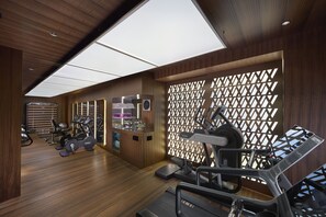 A modern gym with wooden floors, exercise equipment, and a large skylight.