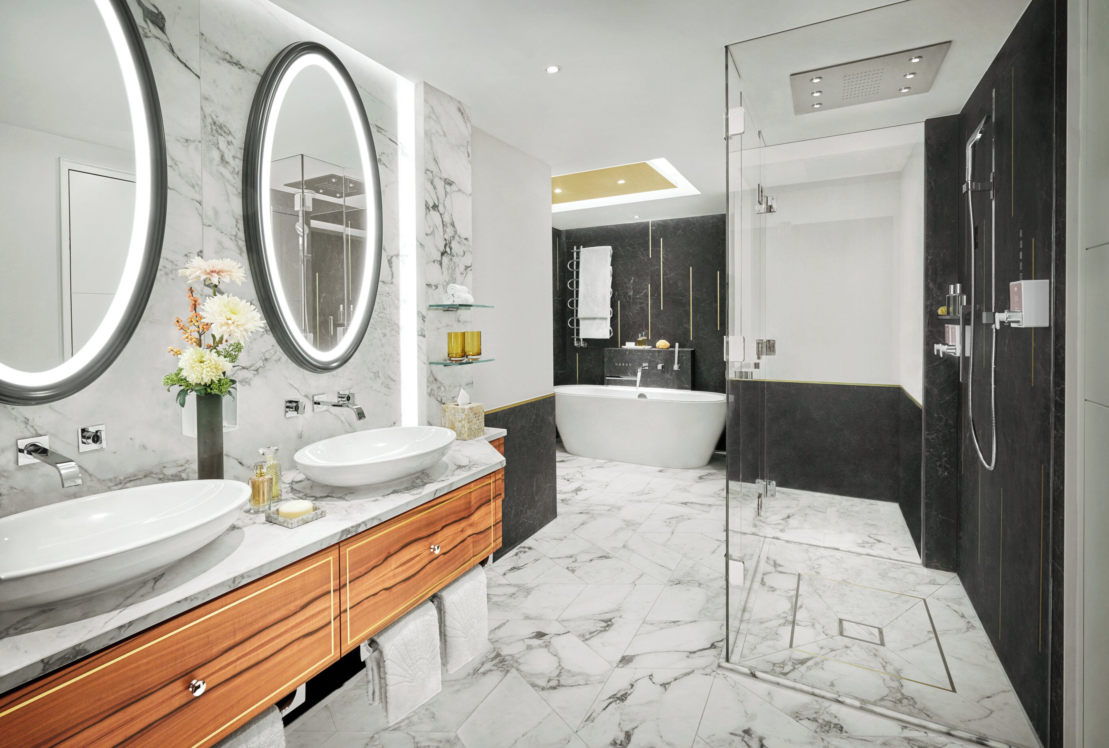 A modern bathroom with two sinks, a large mirror, a bathtub, and a walk-in shower.
