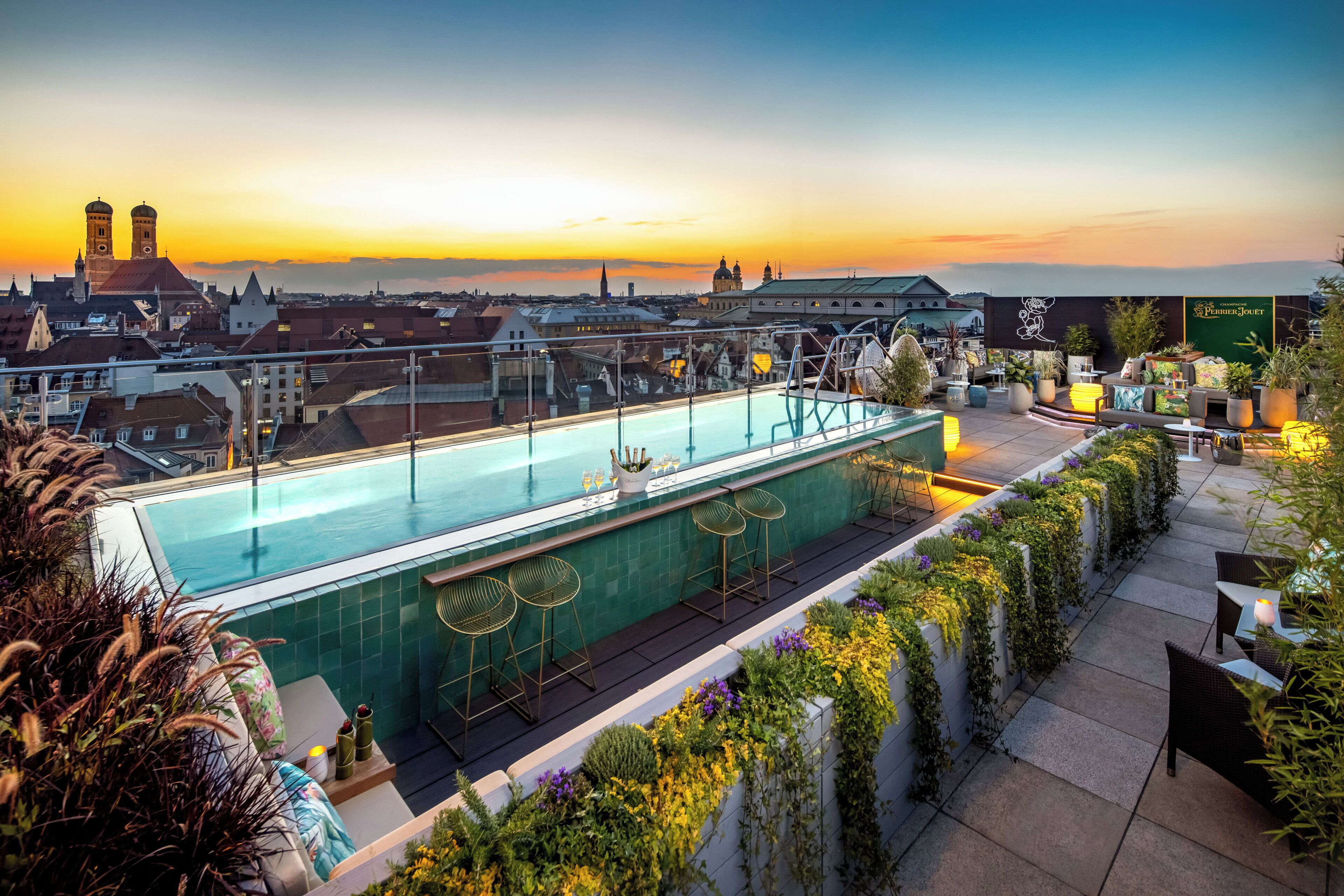 A rooftop pool with a view of a cityscape and a sunset.