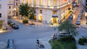 Un hotel de varios pisos con un estilo arquitectónico europeo clásico, que presenta una imponente torre en esquina y una fachada bien iluminada.