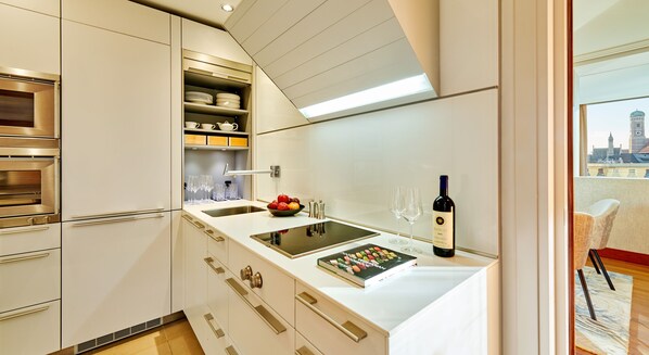 A modern kitchen with a built-in oven, a sink, and a wine bottle on the counter.