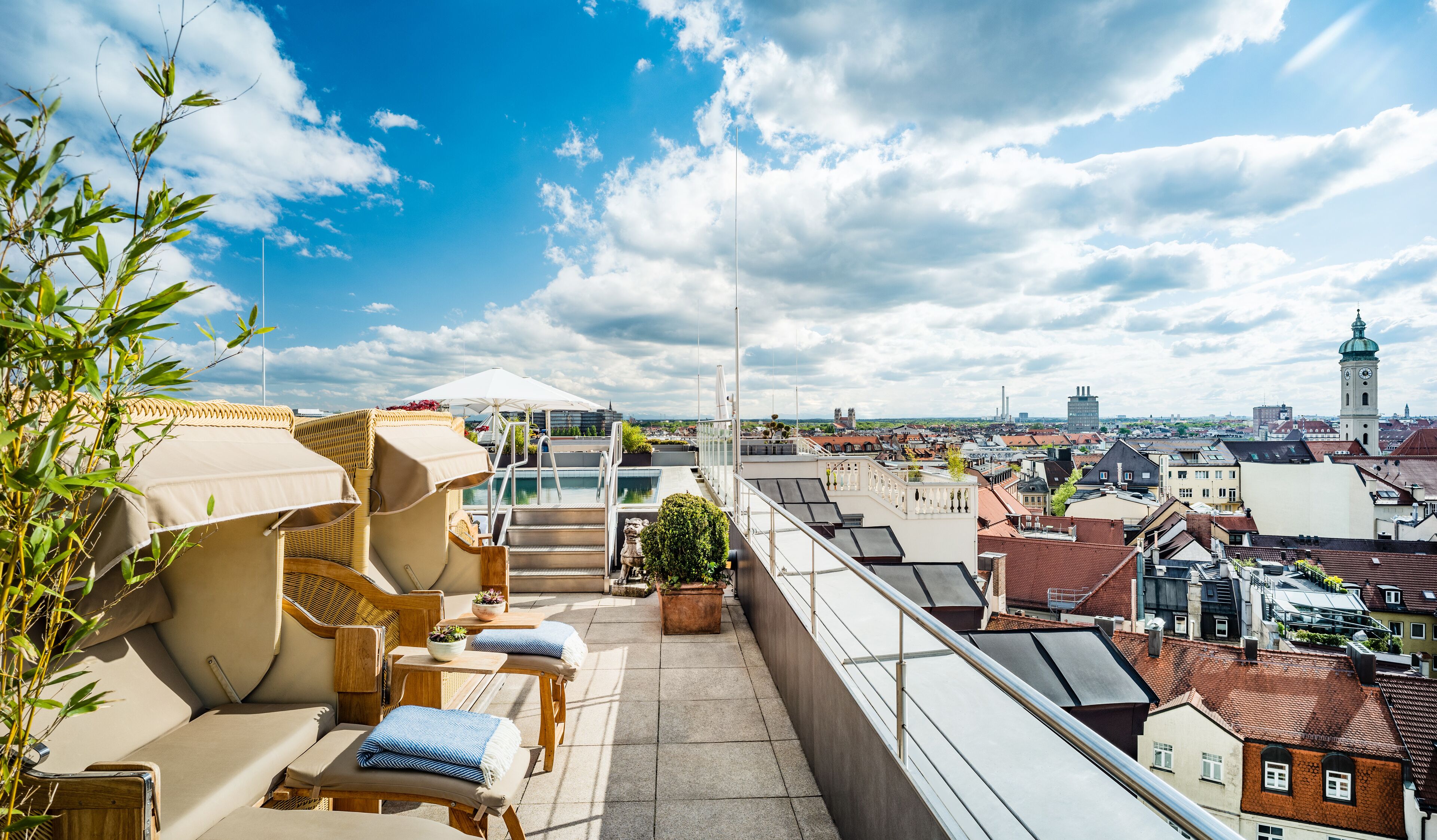 A rooftop terrace with lounge chairs, a small pool, and a city view.