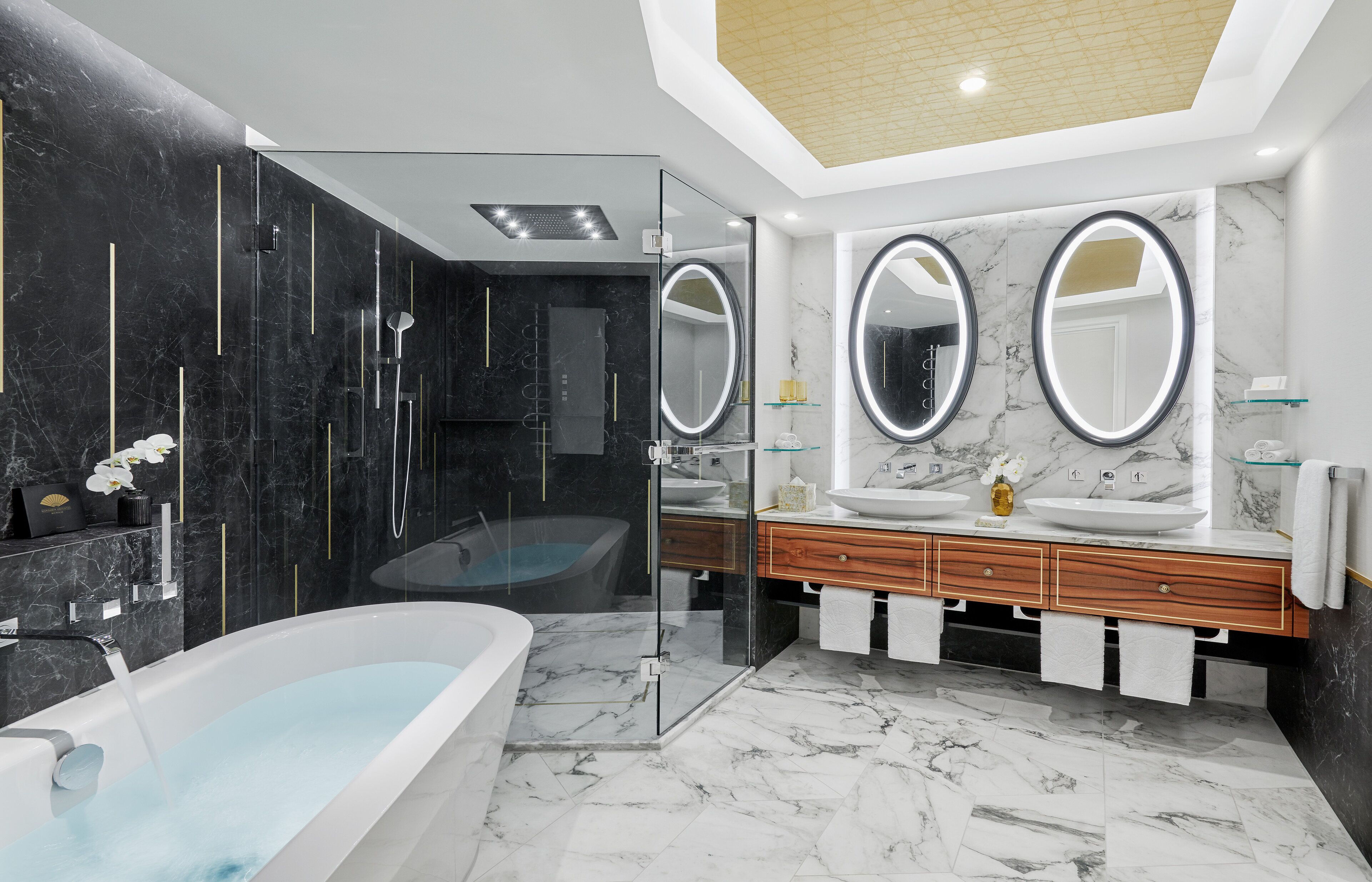 Ein modernes Badezimmer mit einer freistehenden Badewanne, zwei Waschbecken mit runden Spiegeln und einer Duschkabine.