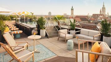 Terraza en la azotea con mobiliario exterior, piscina y vista a la ciudad.