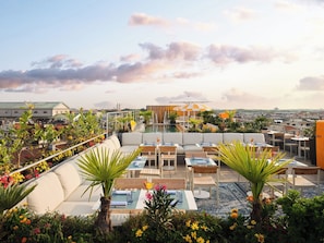 A rooftop terrace with outdoor seating, a pool, and a view of the cityscape.