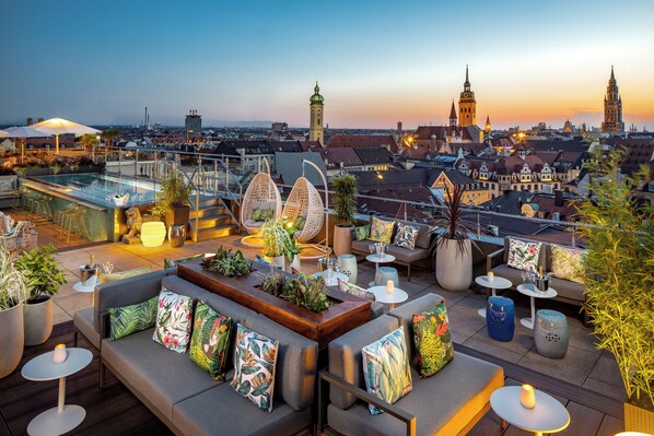 A rooftop terrace with seating, a pool, and a cityscape view.