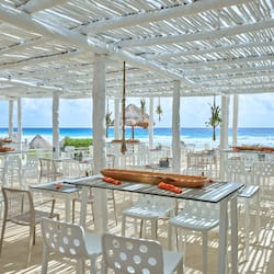 Dine al fresco with ocean views under a shaded pergola.