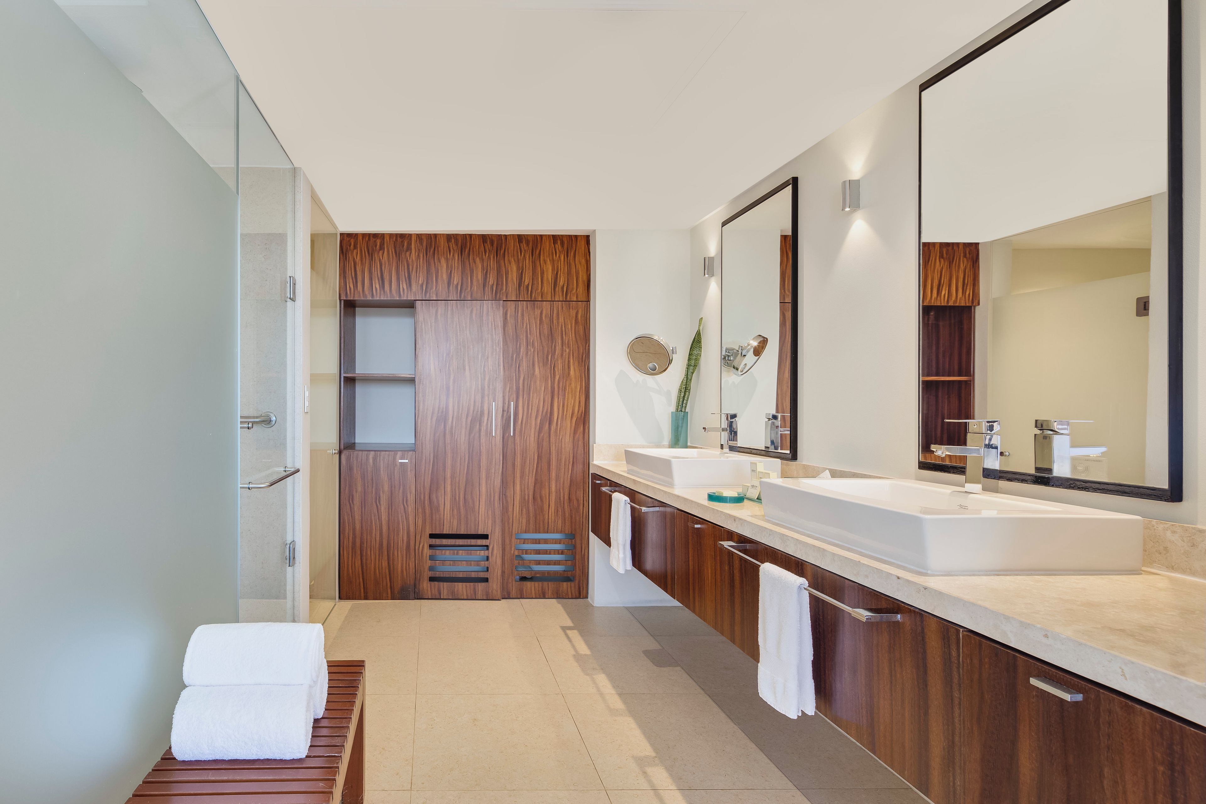 Un bagno moderno con un grande specchio, due lavandini e un mobile bagno in legno.