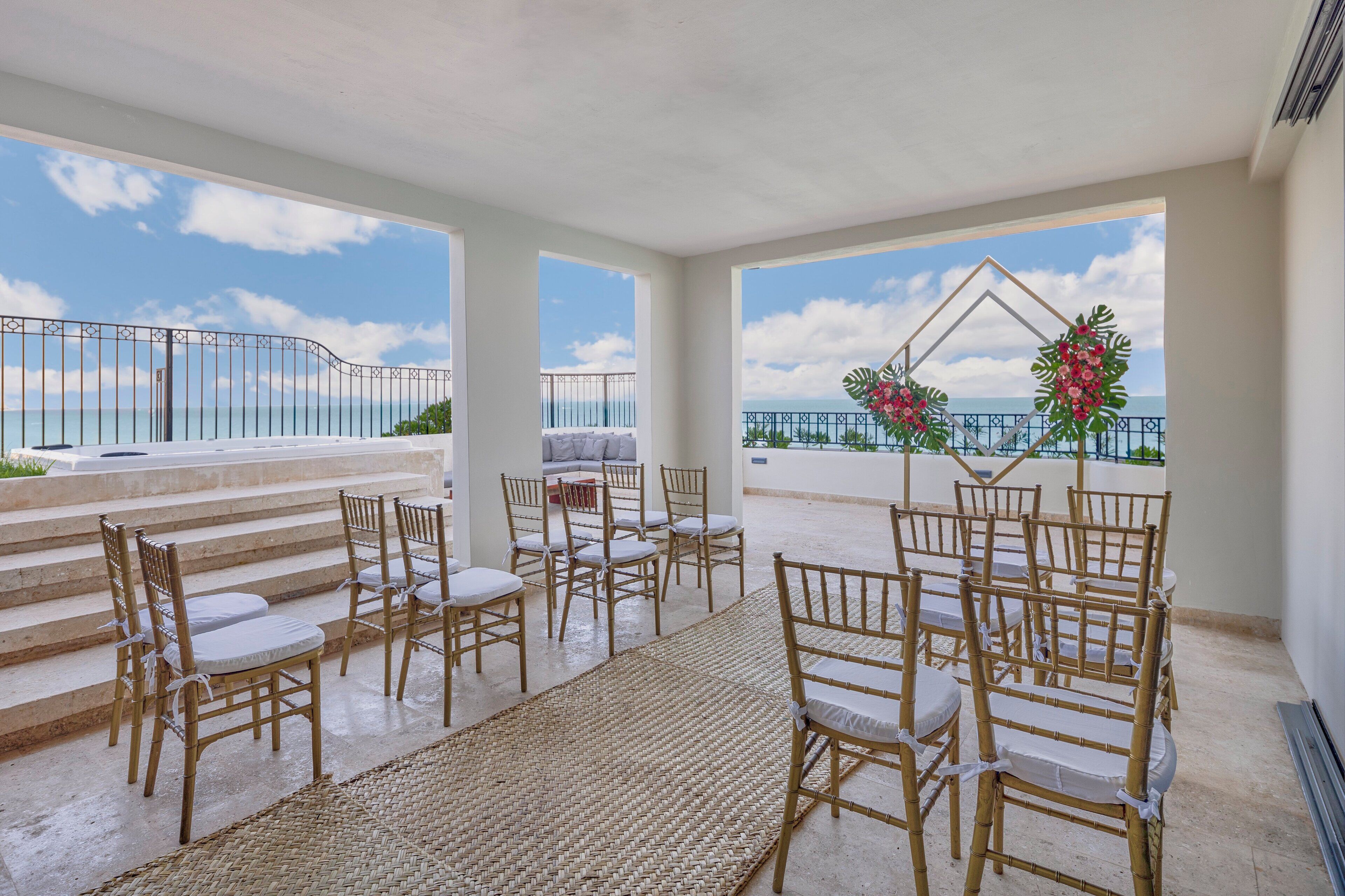 Una terraza con sillones de mimbre y un tapete tejido, con vistas a un paisaje marino.