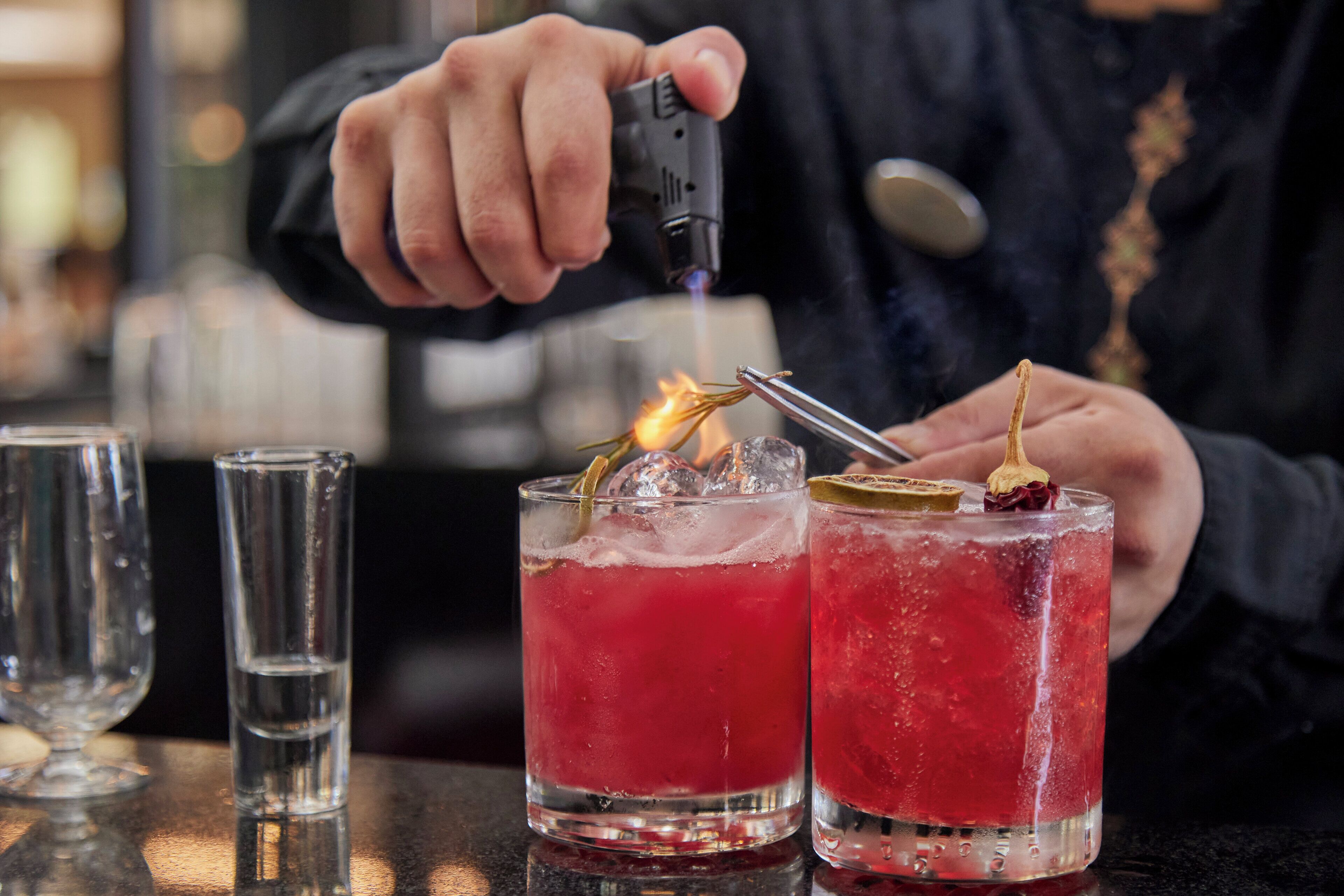 A person using a lighter to ignite a drink in a glass.