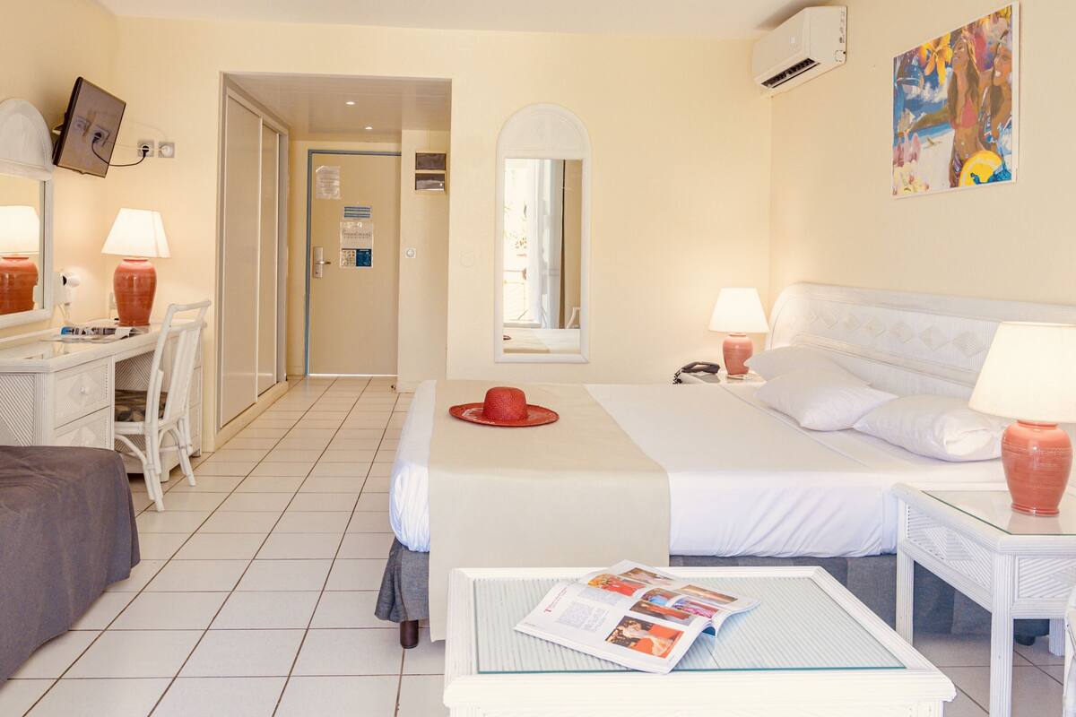 Een hotelkamer met een bed, een bureau, een bank en een klein tafeltje met een tijdschrift.