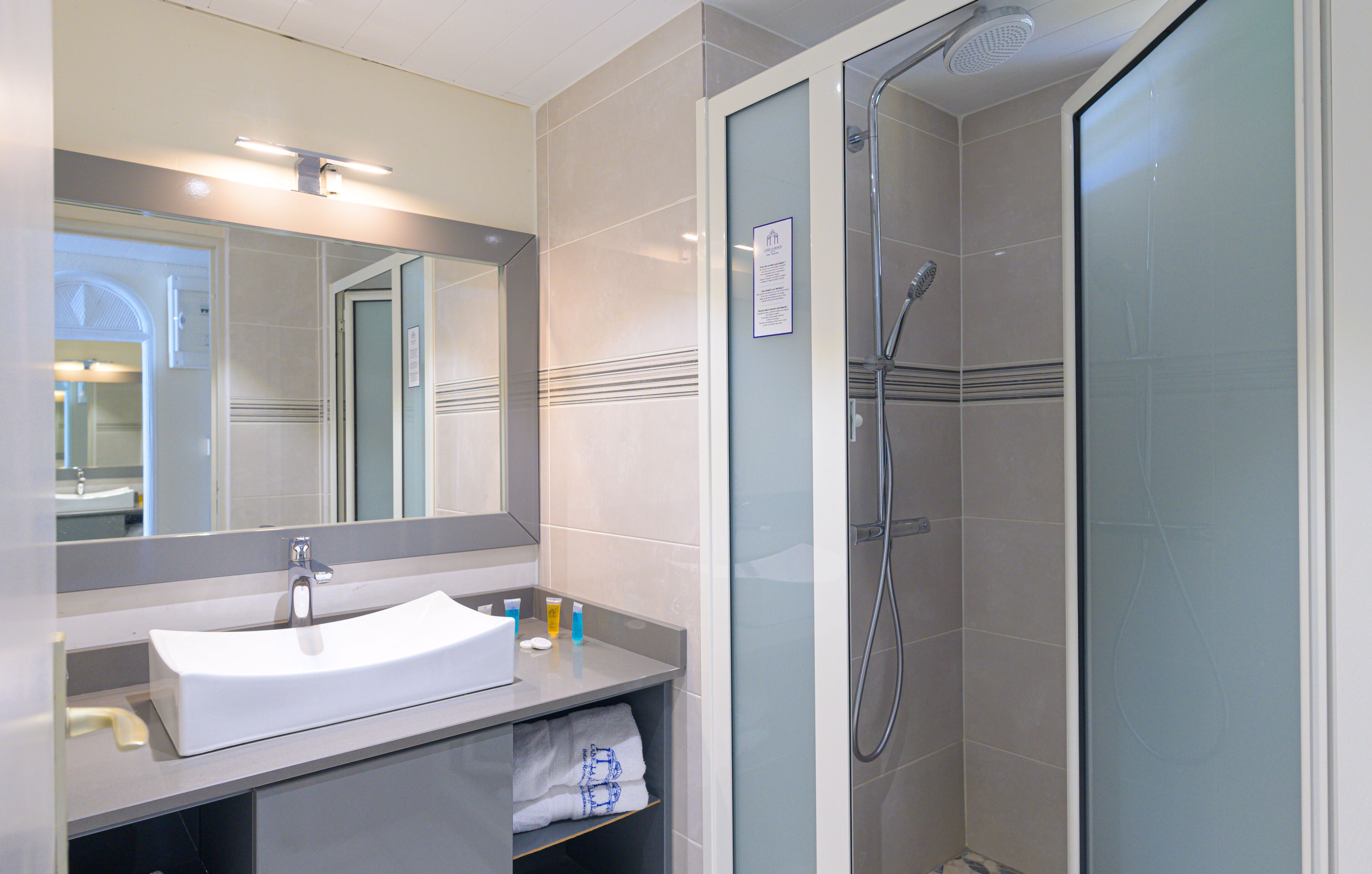 Une salle de bain moderne avec un lavabo blanc, un miroir et une douche en verre.