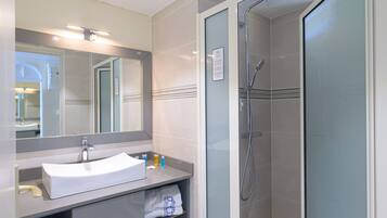 Une salle de bain moderne avec un lavabo blanc, un miroir et une douche en verre.