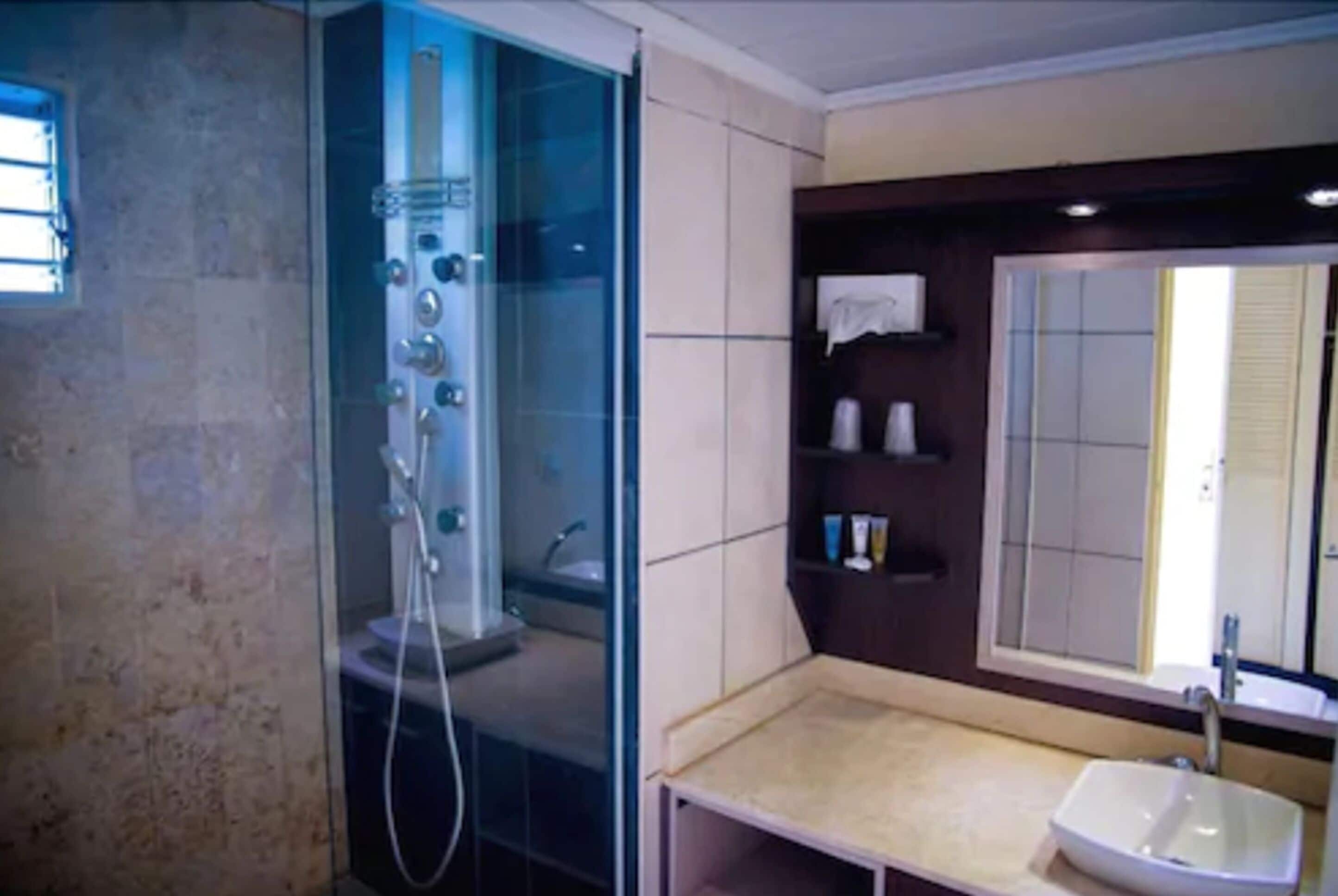 Une salle de bain avec une douche à parois de verre, un lavabo et un miroir.