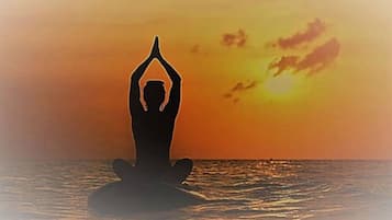 Silhueta de uma pessoa meditando em uma plataforma flutuante, com o pôr do sol ao fundo.