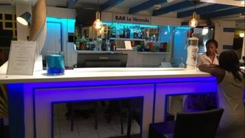 Een bar met een blauw neonbord, een visdecoratie en een toonbank met een menukaart.
