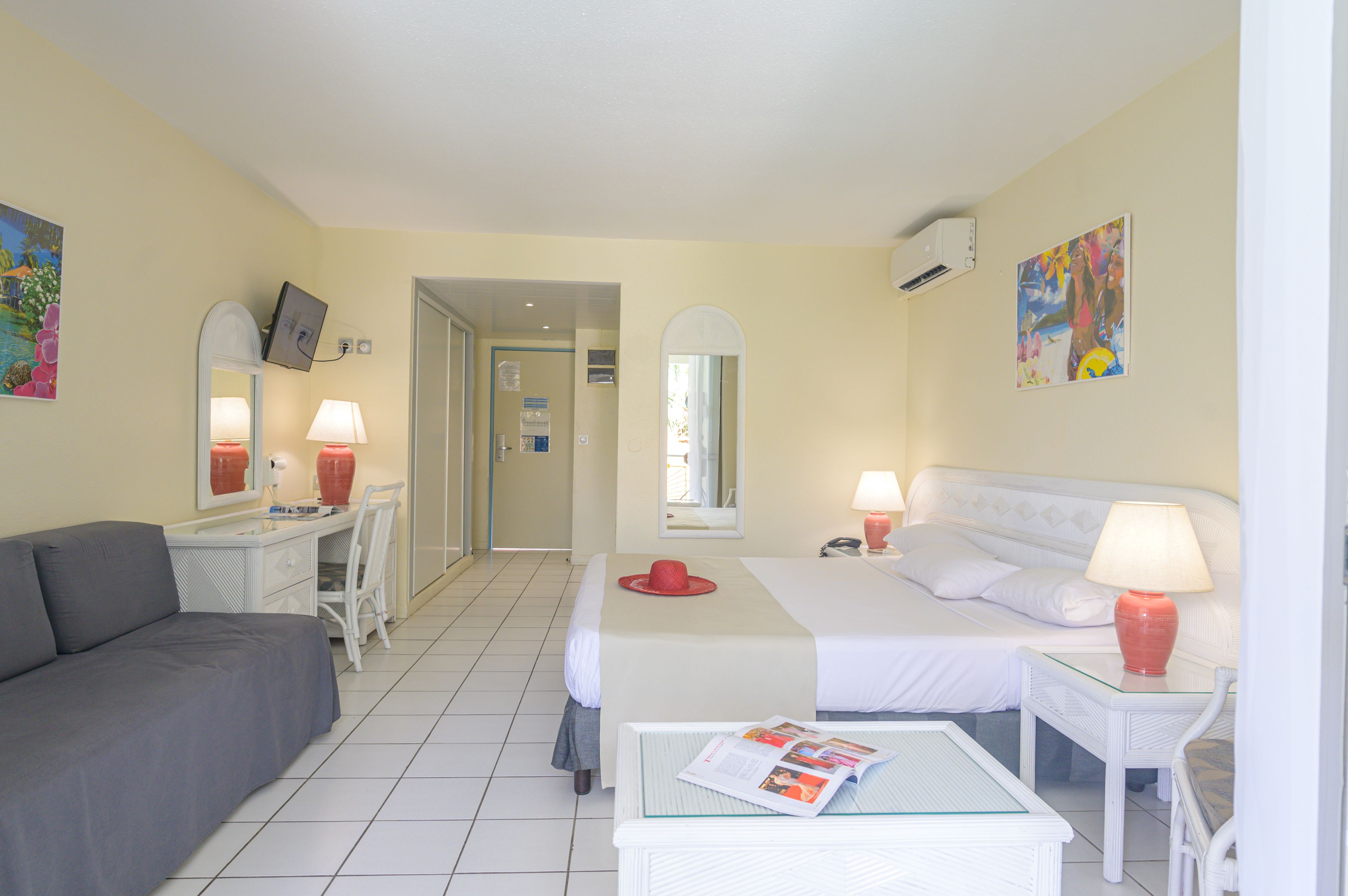 Habitación de hotel con cama, sofá, escritorio y silla. Hay dos lámparas en el escritorio y sobre la cama.