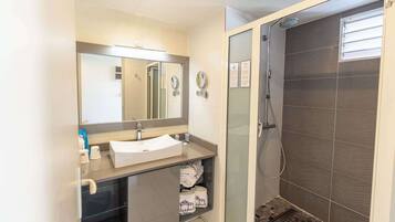 Un baño moderno con lavamanos, espejo, toallero y ducha.