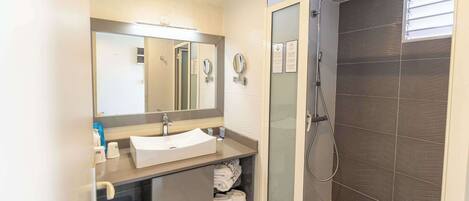 A modern bathroom with a sink, mirror, towel rack, and shower.