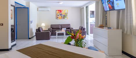 A hotel room with a bed, a sofa, a coffee table, a TV, and a desk.