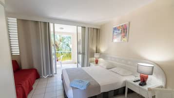 Une chambre d’hôtel avec un lit, une table de chevet, un fauteuil rouge, un balcon avec des rideaux et un tableau au mur.