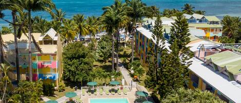 Un resort con piscina, palmeras y vista al océano.