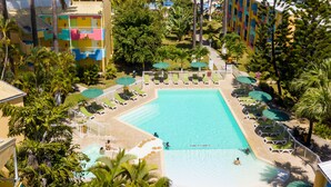 Un resort con piscina, palmeras y vistas al océano.