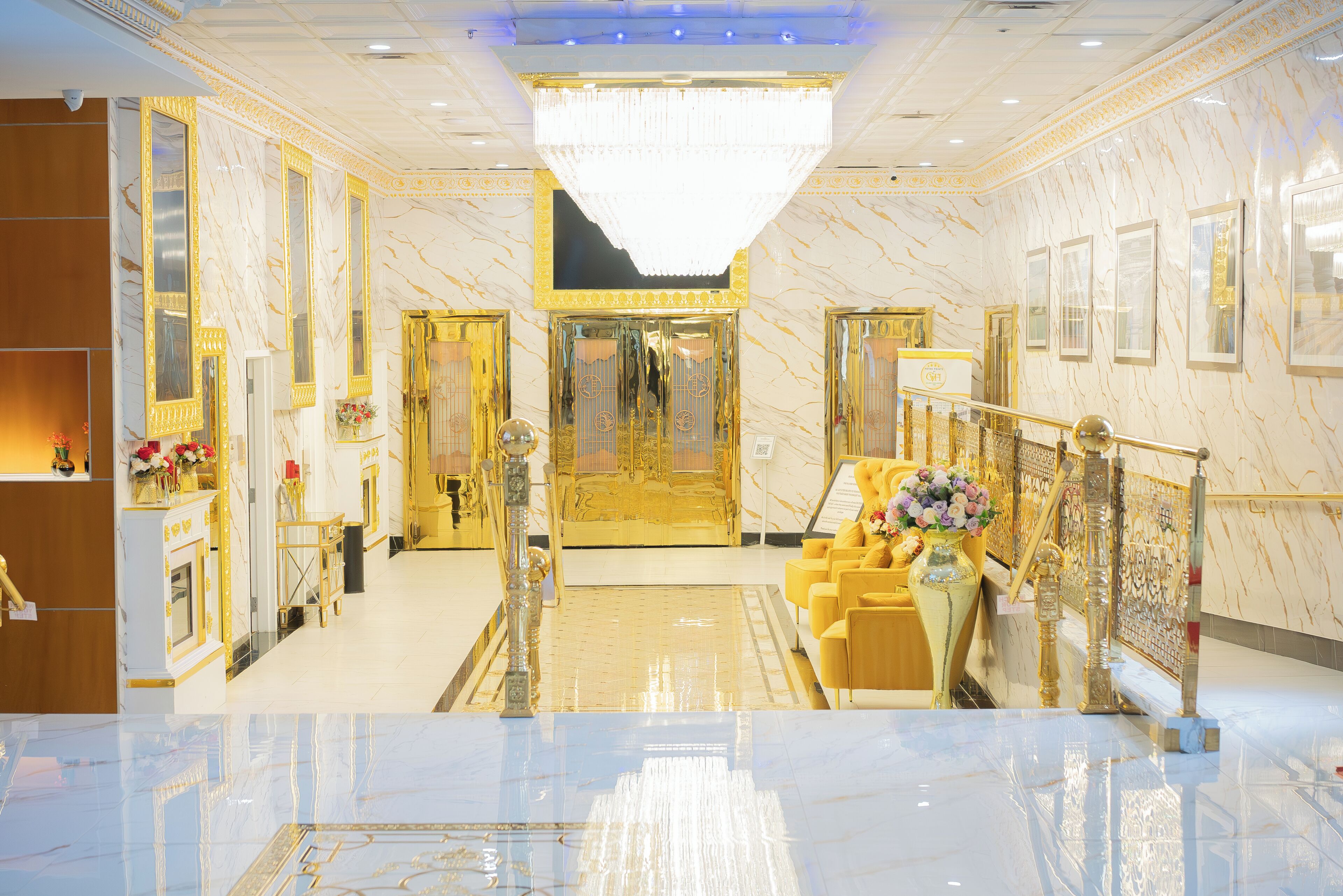 Un hall d’entrée luxueux, avec un sol en marbre, des éléments décoratifs dorés et un magnifique lustre.