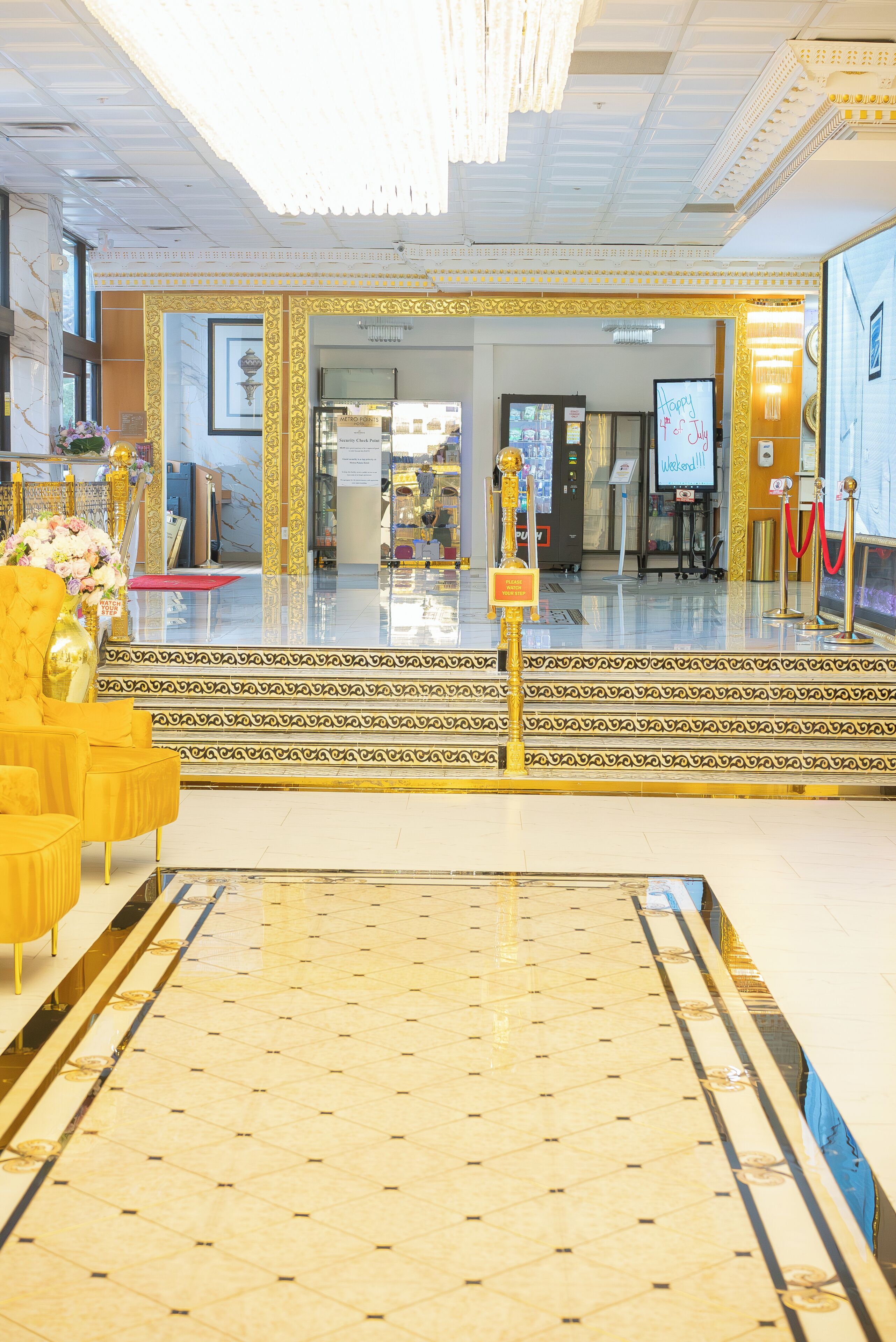 Un vestíbulo de hotel con piso de mármol, columnas decorativas doradas y una recepción.