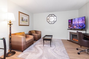 A living room with a sofa, a coffee table, a TV, a fireplace, and a lamp. - Metro Points Hotel (Hyattsville)