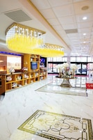 Una hall con pavimento in marmo, un grande lampadario e una reception con scaffali di libri e fiori.