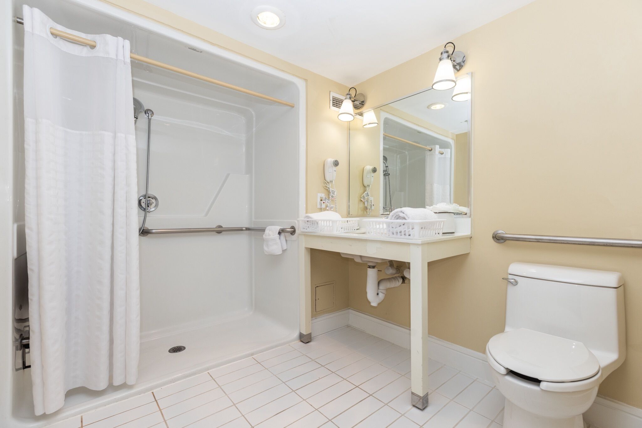 A bathroom with a shower, toilet, sink, and mirror.