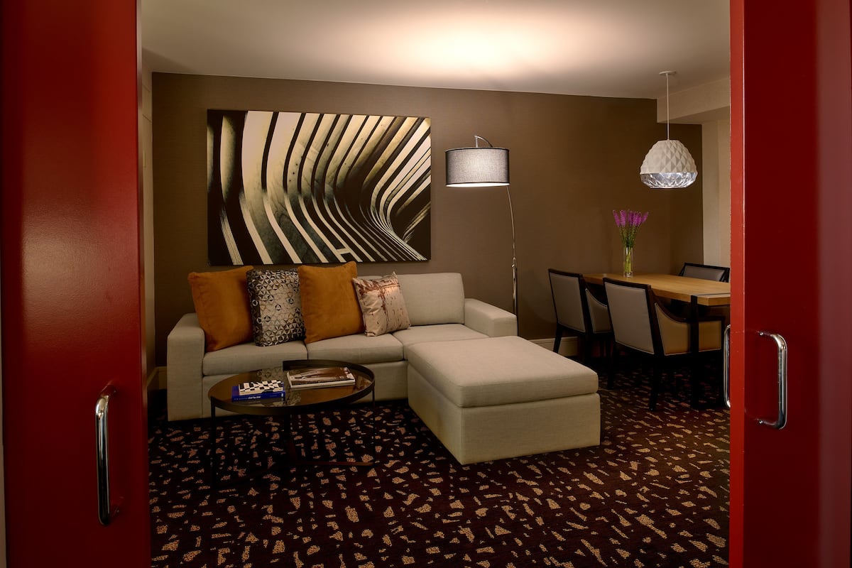 Una sala de estar moderna con un sofá modular, una mesa de centro, una lámpara de pie y una zona de comedor con sillas y una mesa.