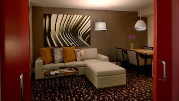 A modern living room with a sectional sofa, a coffee table, a floor lamp, and a dining area with chairs and a table.