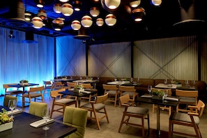 A restaurant with multiple tables and chairs, blue lighting, and hanging pendant lights. - Kimpton Hotel Palomar Los Angeles Beverly Hills by IHG (Los Angeles)