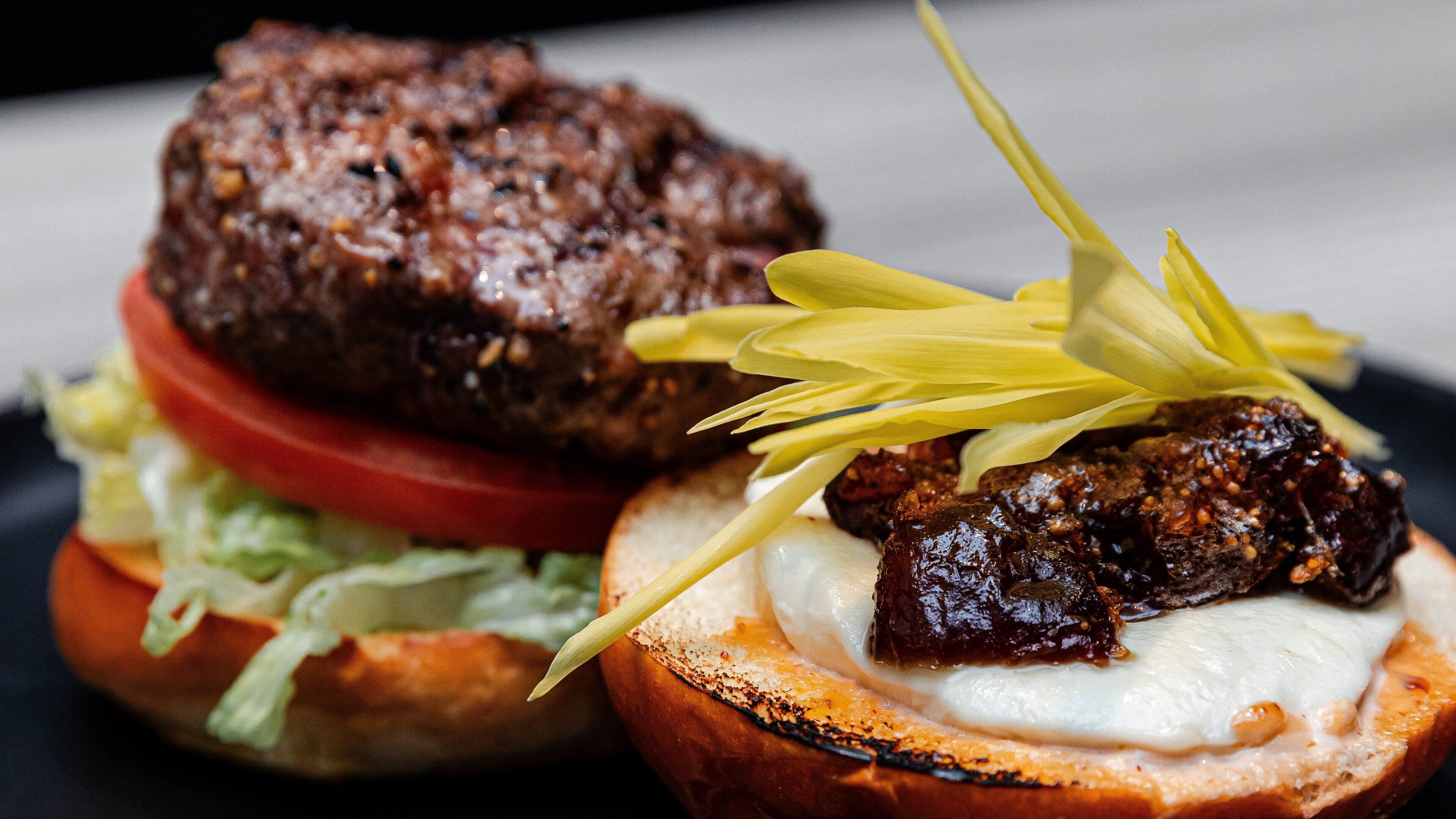 A burger with a toasted bun, lettuce, tomato, and a meat patty.