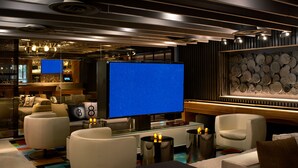 Ein modernes Hotelzimmer mit großem Flachbildfernseher, bequemen Sitzmöglichkeiten, einer Bar und einer Wand mit dekorativen Tellern.