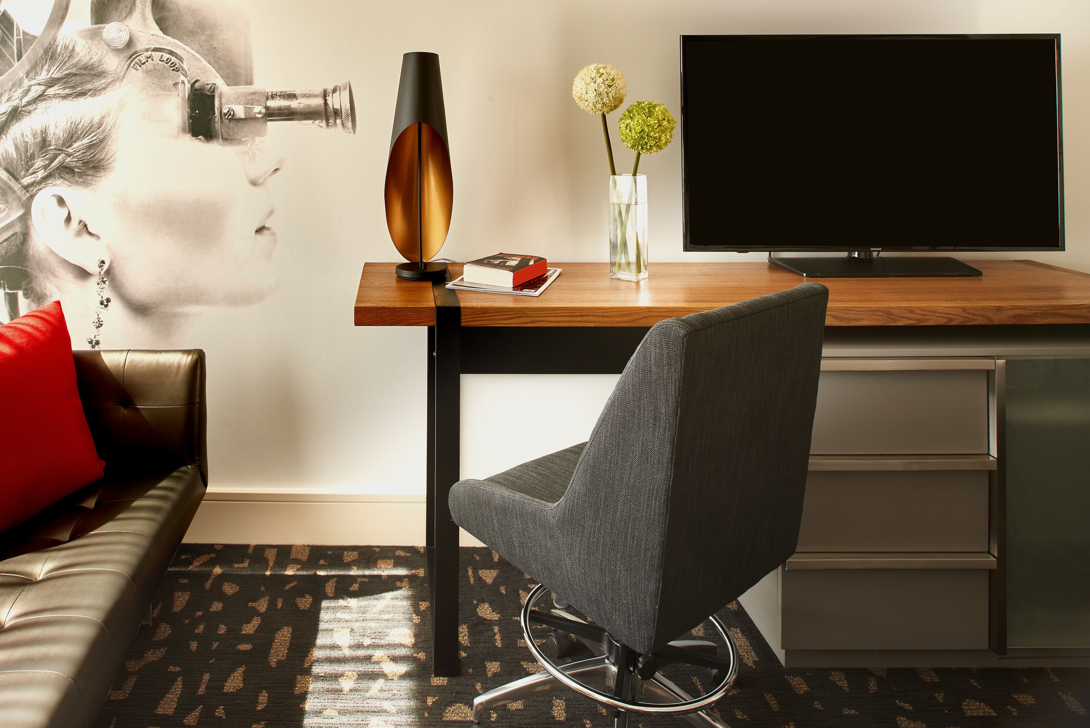 A modern living room with a sofa, a coffee table, a TV, and a decorative vase with flowers.
