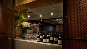 Eine Bar mit Weinflaschen und Gläsern, Holzvertäfelung und einer dekorativen Blumenkomposition.