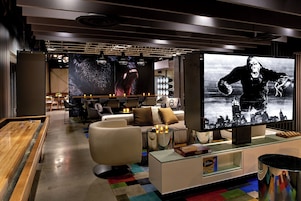 Un'area lounge moderna con tavolo da calcio, comodi posti a sedere, un ampio televisore a schermo piatto e un set di Scarabeo su un tavolo in vetro.