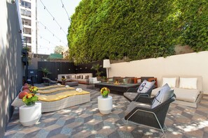 Un espace extérieur aménagé avec des canapés, des fauteuils et un foyer.
