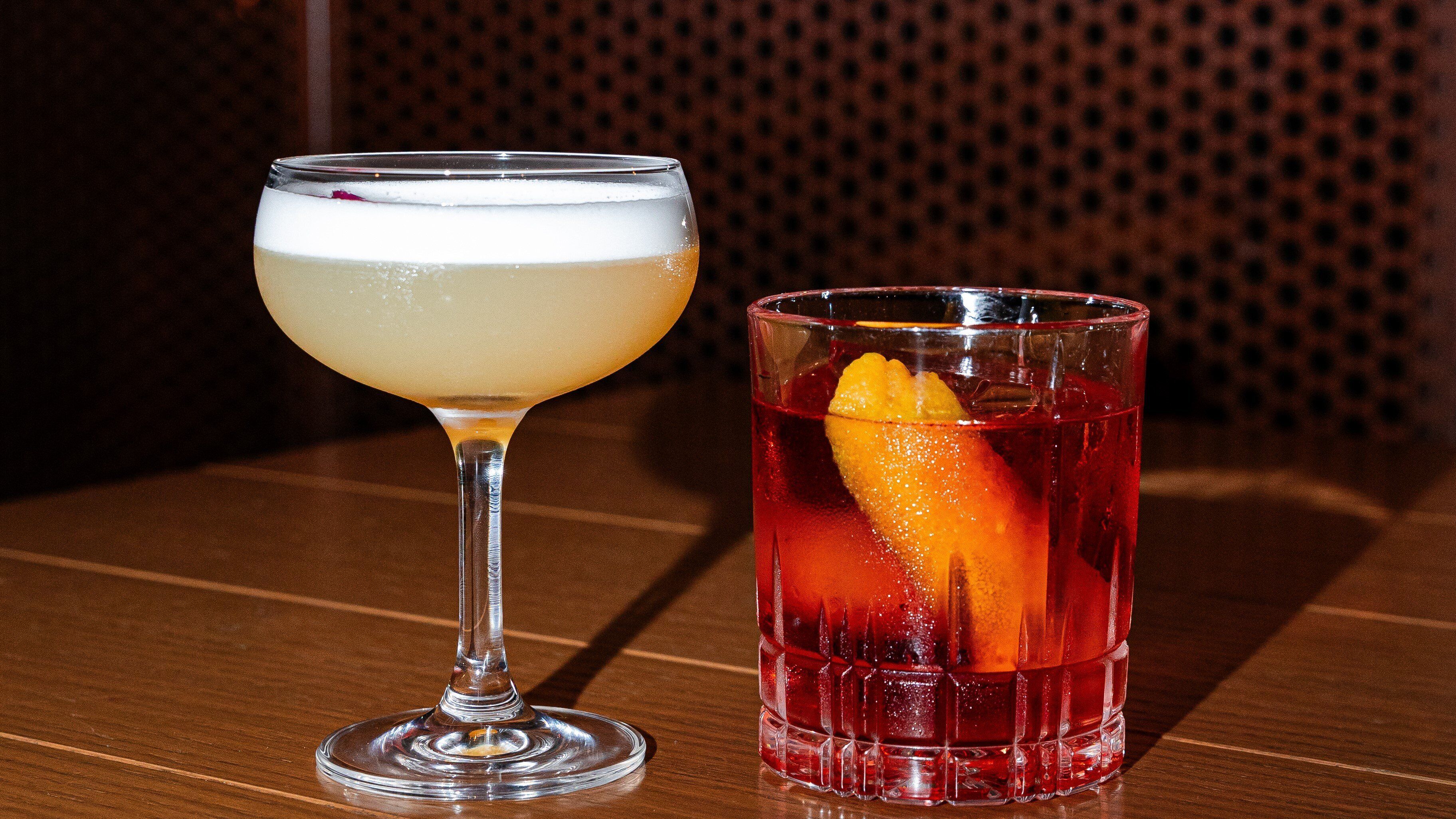 Two glasses of beverages on a wooden table.